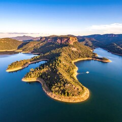 Aerial view of a peninsula jutting into a tranquil lake, surrounded by mountains