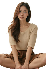 A captivating studio portrait of a young Asian woman with a serene expression, sitting cross-legged.