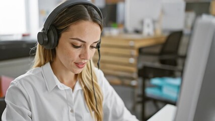 Woman working at computer with headset in office environment. - Powered by Adobe