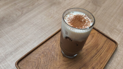 A glass of traditional teh tarik (pulled tea) with a distinctive layer of foam, served at a restaurant table in the evening. This warm beverage is popular in Southeast Asian eateries.