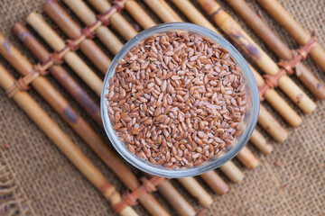 Brown flax seeds in a glass bowl on a bamboo mat