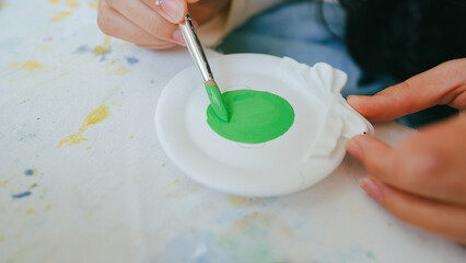 Hand painting on white plaster craft with green acrylic paint, representing creativity, hobby, and artistic expression in DIY arts.