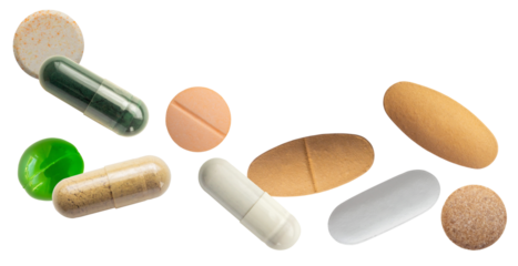 photograph of a horizontal arrangement of diverse health supplements and prescription pills, including capsules and various shaped tablets, dramatically isolated on black.