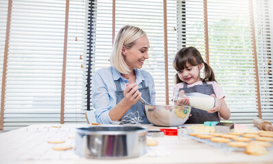 Portrait of little caucasian girl and mother baking cooking cookies in the kitchen. Happy fun caucasian family love together parenthood food nutrition, love together mother’s day concept banner