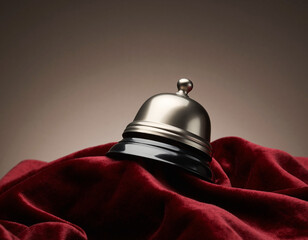 Silver service bell rests on red velvet cloth in elegant hotel, creating a sense of luxury and anticipation for impeccable service.