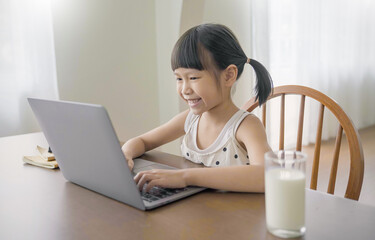 Portrait of Asian girl using computer to learn lessons in elementary school. Student nerd glasses girl study in primary. Children gadgets in classroom. Education knowledge, technology internet network