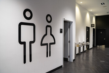 Interior view of modern public restroom entrance with minimalist wall signs.