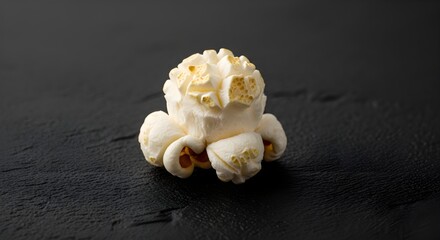 Enjoy a single piece of fluffy popcorn for movie night or a tasty snack on a dark background that is perfect for a vibrant food blog post