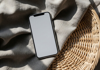 Top View of Smartphone with Gray Screen on Woven Basket and Textured Cloth Underneath in Neutral Light