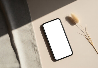 Top View of Smartphone with Blank White Screen on Beige Background with Shadows and a Decorative Grass Plant with Gray Woolen Fabric