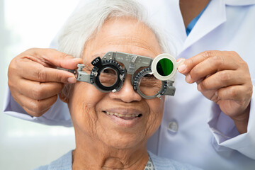 Asian senior woman wearing ophthalmic vision eye test and using optical trial frame.