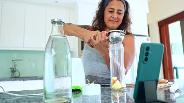 Sporty woman squeezing fresh lemon juice for a healthy smoothie
