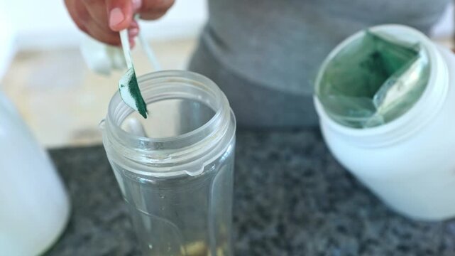 Woman preparing a protein shake with green spirulina powder