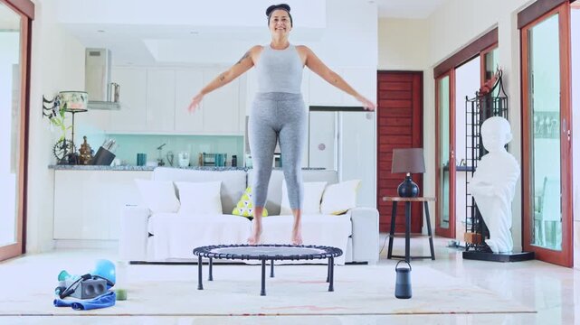 Fit woman doing cardio workout jumping on mini trampoline at home