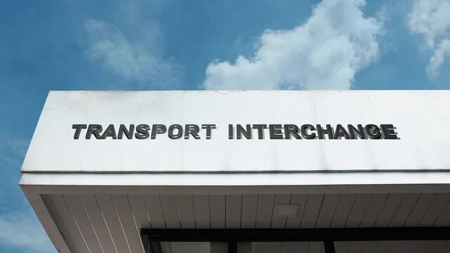 Transport Interchange word sign displayed on a large transportation building under a clear blue sky, symbolizing connectivity, public transit, logistics, infrastructure, multimodal travel, and urban