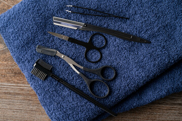紺色のタオルの上に置かれた眉毛の手入れの道具セット