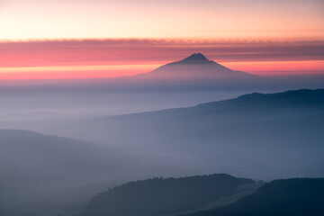 Misty mountain peak at sunrise with colorful sky and layered landscape