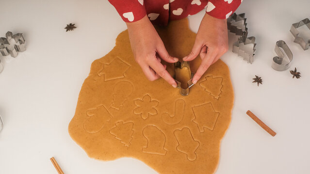 Top view of a table with gingerbread cookies being made by a young woman. Cookie cutters and dough on the table. Gingerbread man, Christmas tree and snowflake.