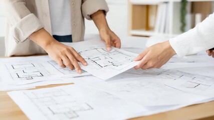 Blueprint Collaboration: Two individuals work closely over detailed architectural blueprints on a sunlit table, engaging in collaborative discussion and planning