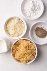 Farfalle pasta with cheese and black pepper, ingredients for Italian cooking on white background