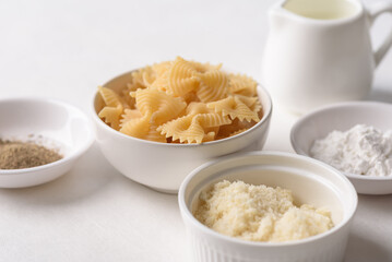 Farfalle pasta with cheese and black pepper, ingredients for Italian cooking on white background