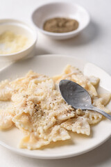 Farfalle pasta with white cream cheese sauce and black pepper, Italian food on a white plate