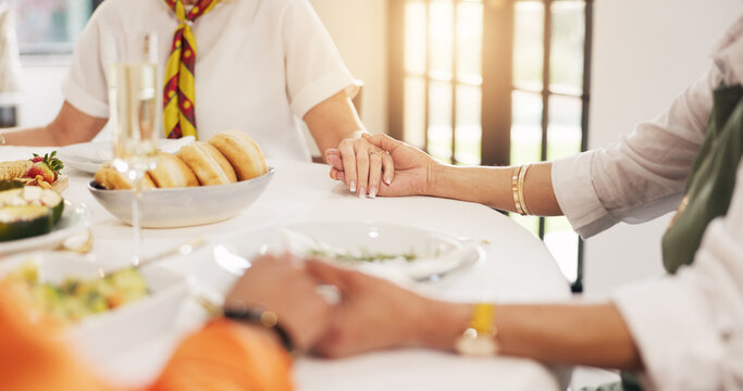 People, holding hands and praying with food on dining table for gratitude, appreciation and faith. Group, friends or social gathering with trust, meal or hope for culture, feast or tradition in home - Powered by Adobe