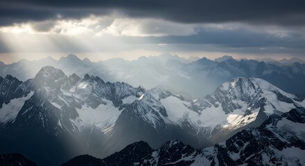 Dramatic Sun Rays Over Snow Capped Mountain Range Under Stormy Clouds