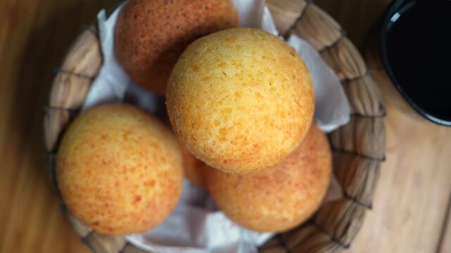 Close-up of freshly baked Colombian almoj&aacute;banas in a rustic basket. Warm tones, soft lighting highlight the cheese bread's texture. A cozy and appetizing visual.