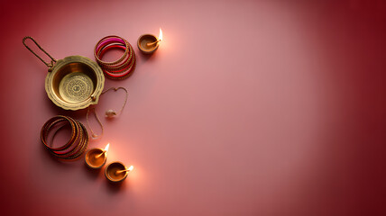 Traditional Indian wedding accessories including bangles, a brass pot, and lit oil lamps arranged on a red background