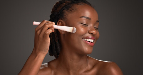 Black woman, makeup brush and happy in studio with beauty, foundation and space on dark background....