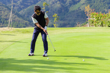 ゴルフを楽しむ日本人のミドル男性