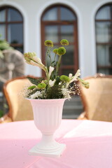 Elegant white floral centerpiece on pink tablecloth.