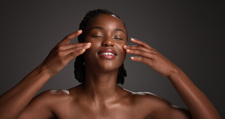 Fototapeta premium Skincare, natural beauty and black woman with hands in studio for hydration, wellness and cosmetics. Space, dermatology and person with touch, smile and aesthetic for healthy skin on dark background