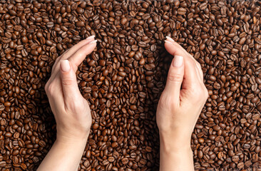 Female hands gently cupping roasted coffee beans. Concept of aroma, freshness, caffeine and morning energy. Close-up view of coffee culture and natural brown texture.