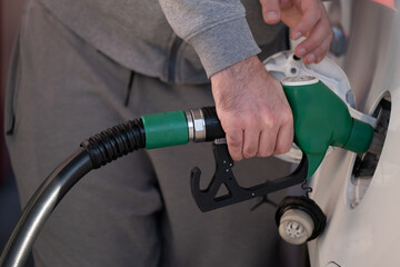 Man refueling a car at gas station with green fuel nozzle