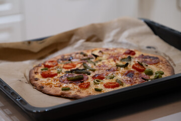 Fresh baked homemade pizza on baking tray with melted cheese