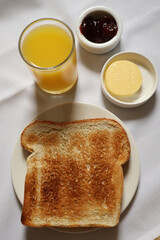 Simple continental breakfast with toast, orange juice, jam, and butter. Cotswolds countryside, England