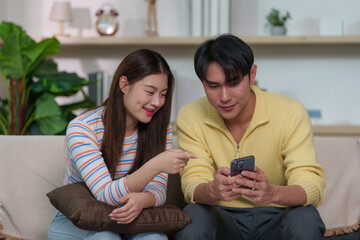 Joyful couple sharing a moment while using smartphones indoors