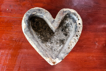 A close-up of a heart-shaped stone ashtray placed on a wooden surface.