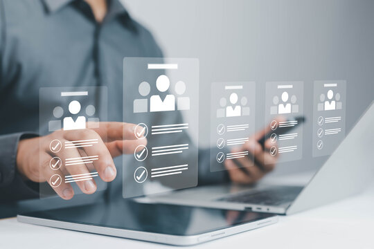 Businessman using laptop with virtual interface for online recruitment and human resources management, selecting candidate profiles. Concept of HR technology, digital hiring, and modern workforce