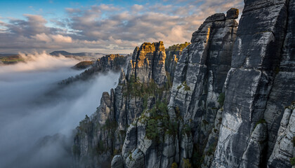 Jagged rock formations emerge from a sea of fog at sunrise.
