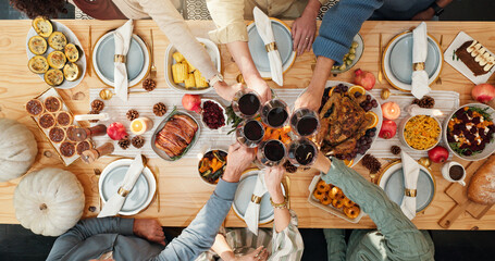 Thanksgiving, wine and cheers with hands of family for festive feast, celebration and dinner. Toast, alcohol drink and holiday season with above of people and glass in dining room of home for reunion