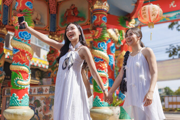 Fototapeta premium Young asian women enjoying friendship and taking selfie at temple