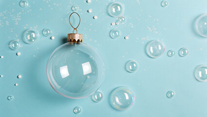 Clear ornament surrounded by bubbles on a light blue background during the holiday season