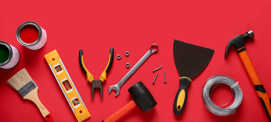 Paint and construction tools on red background