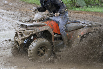 Thrilling off road adventure with man riding quad bike on muddy trail. An action shot of an extreme sport with splash of mud, showcasing speed and pure excitement outdoors