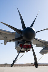 Detailed view of an eight-blade propeller and engine nacelle showing the aerodynamic hub and propeller blades of a military transport aircraft on the ground