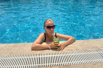 A retired woman enjoys a cold lemonade in the pool