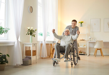 Happy and friendly man senior patient in a wheelchair enjoying a fun ride with a male doctor or...